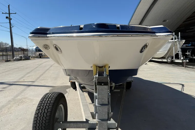 Slide: The Image of 2014 Chaparral 264 Sunesta boat on trailer, parked outdoors under clear blue sky. - 3