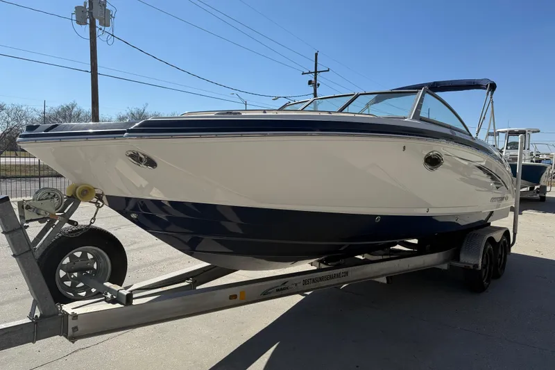Slide: The Image of 2014 Chaparral 264 Sunesta boat on trailer, parked outdoors under clear sky. - 4