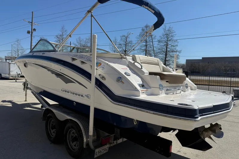 Slide: The Image of 2014 Chaparral 264 Sunesta boat on trailer, parked outdoors under clear blue sky. - 5