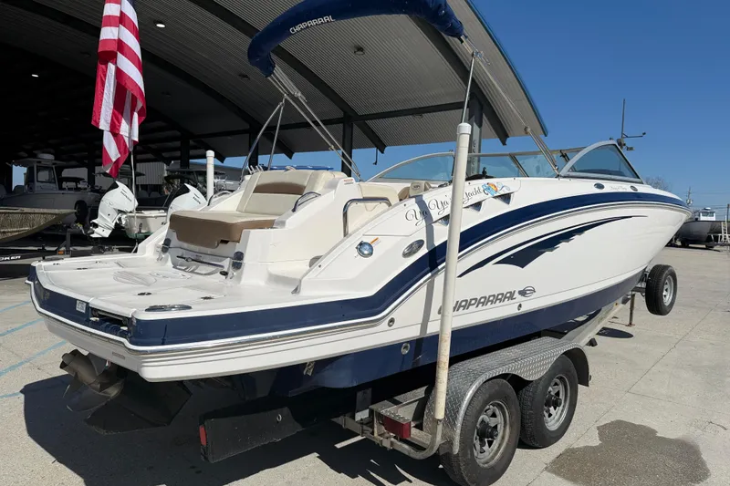Slide: The Image of 2014 Chaparral 264 Sunesta boat on trailer, displayed outdoors with American flag. - 7