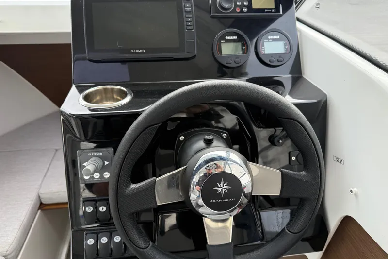 Slide: The Image of 2024 Jeanneau NC 695 Sport helm with steering wheel, controls, and Garmin display. - 11
