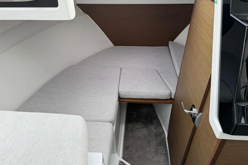Slide: The Image of 2024 Jeanneau NC 695 Sport cabin interior with gray cushions and wooden accents. - 23