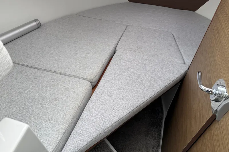 Slide: The Image of 2024 Jeanneau NC 695 Sport cabin interior with gray cushions and wooden door. - 25