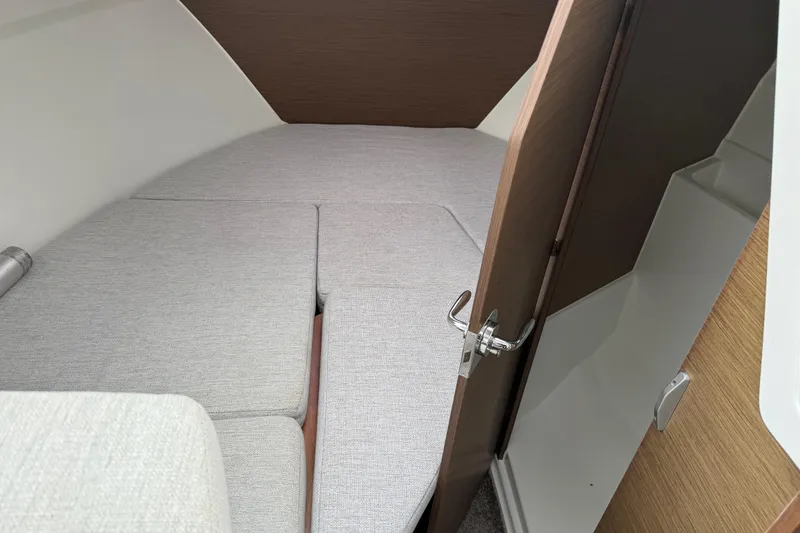 Slide: The Image of 2024 Jeanneau NC 695 Sport cabin interior with gray cushions and wooden accents. - 26