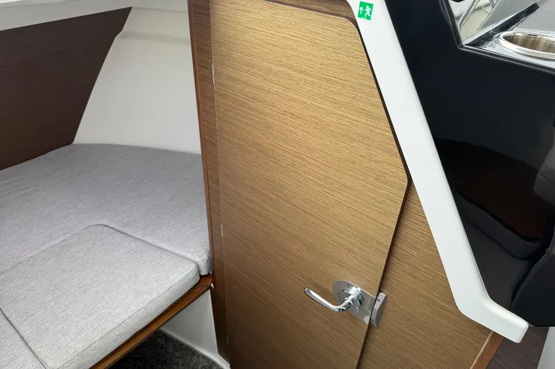 Slide: The Image of 2024 Jeanneau NC 695 Sport cabin interior with wooden door and cushioned bed. - 27