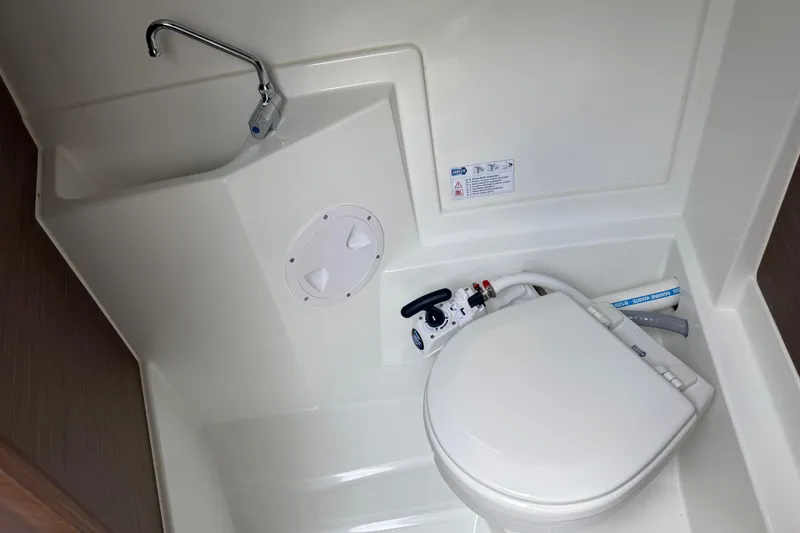 Slide: The Image of 2024 Jeanneau NC 695 Sport boat bathroom with compact toilet and sink. - 28