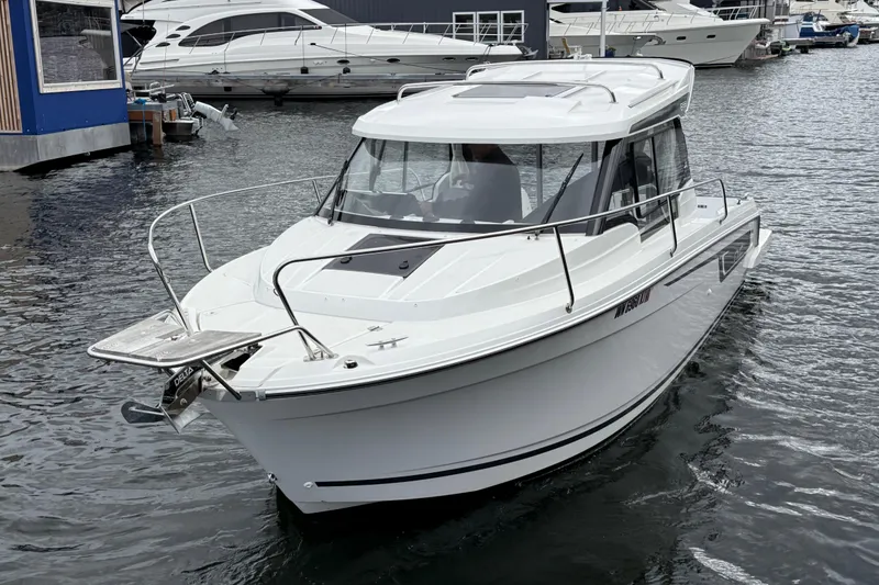Slide: The Image of 2024 Jeanneau NC 695 Sport boat docked in a marina, showcasing sleek design. - 6