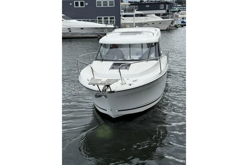 Slide: The Image of 2024 Jeanneau NC 695 Sport boat on water, docked near other vessels. - 7