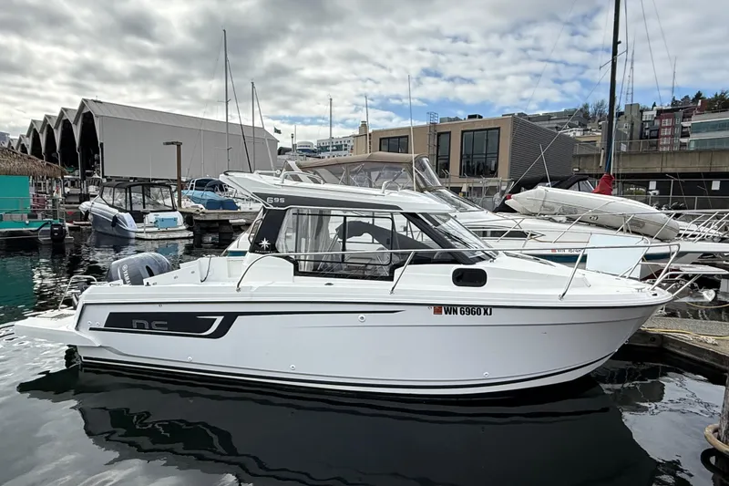 Slide: The Image of 2024 Jeanneau NC 695 Sport boat docked at a marina under cloudy skies. - 8