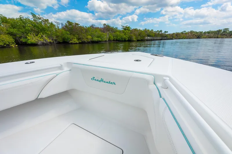 Slide: The Image of 2024 SeaHunter 28 Floridian boat interior with white seating, on a calm river. - 5