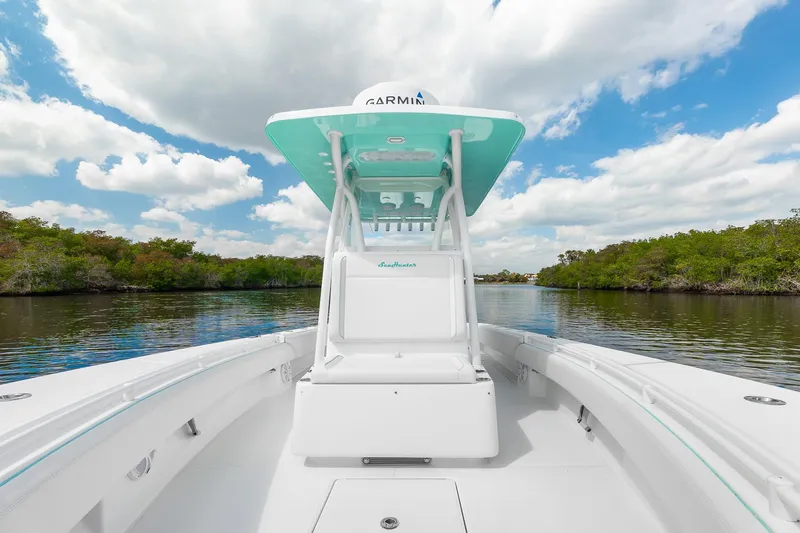 Slide: The Image of 2024 SeaHunter 28 Floridian boat on a serene river, under a bright blue sky. - 7