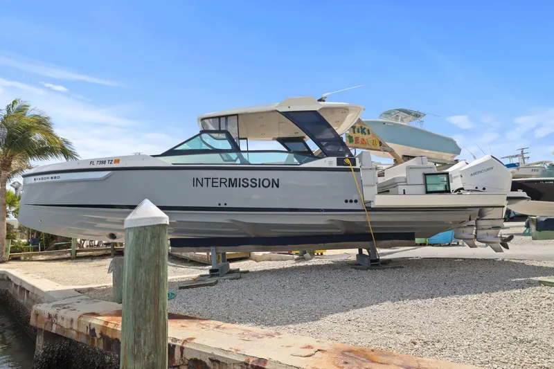 The Image of 2025 Saxdor 320 GTO boat on dry dock, labeled "INTERMISSION," with twin Mercury engines. - 2