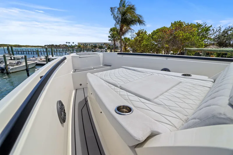 Slide: The Image of 2025 Saxdor 320 GTO boat interior with cushioned seating and cup holders, dockside view. - 42