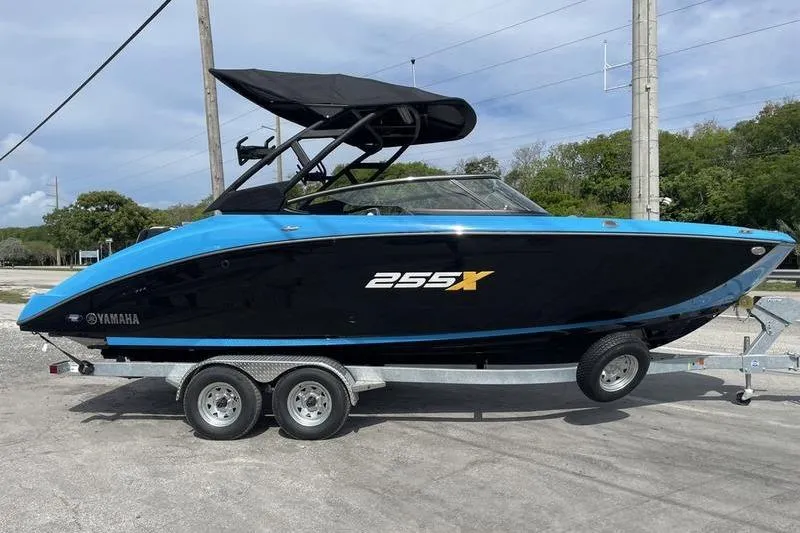 Slide: The Image of 2023 Yamaha Boats 255XD on trailer, black and blue design, parked outdoors. - 10