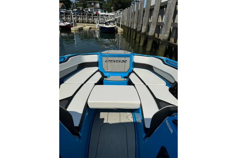 Slide: The Image of 2023 Yamaha Boats 255XD interior with sleek seating, docked at marina. - 8