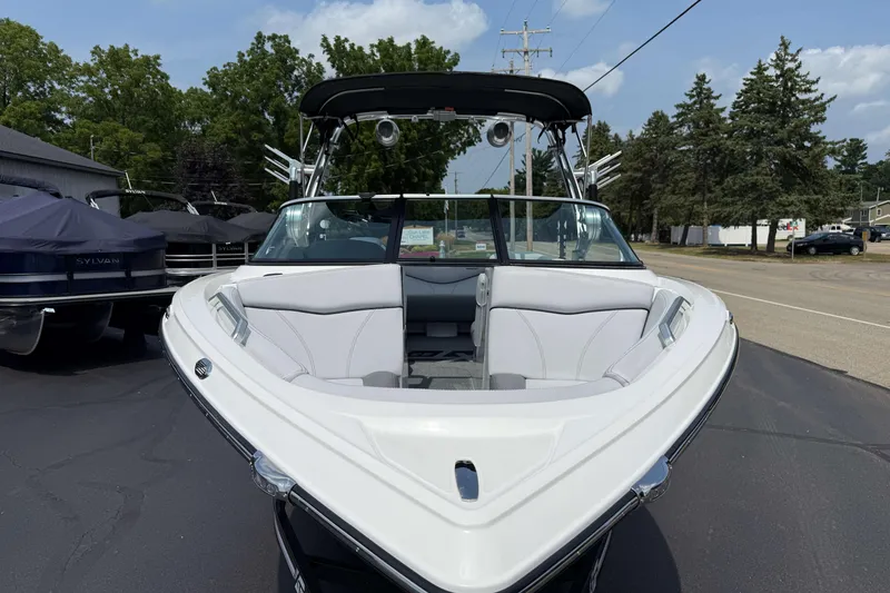 Slide: The Image of 2020 MasterCraft XT23 boat with sleek white interior, parked outdoors. - 22