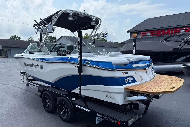 Slide: The Image of 2020 MasterCraft XT23 boat with blue and white design on a trailer. - 24