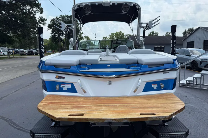 Slide: The Image of 2020 MasterCraft XT23 boat, blue and white, rear view with wooden swim platform. - 25