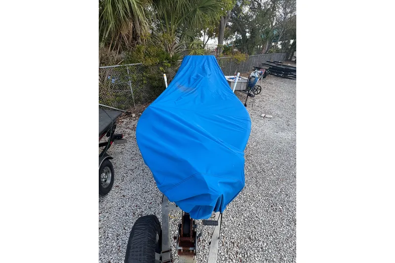 Slide: The Image of 1994 Hewes Redfisher 18 boat covered with blue tarp, parked on gravel. - 15