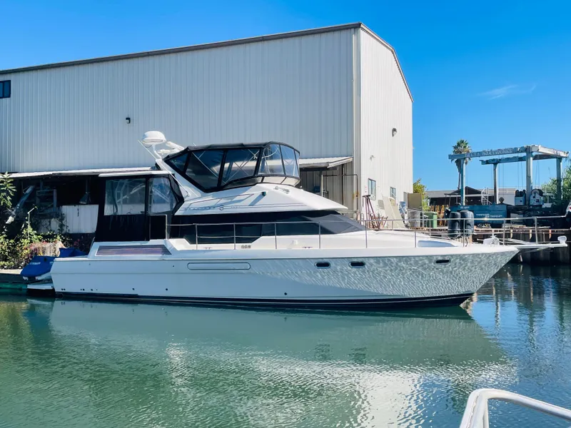The Image of 1995 Bayliner 4587 Motoryacht docked near a marina warehouse. - 0