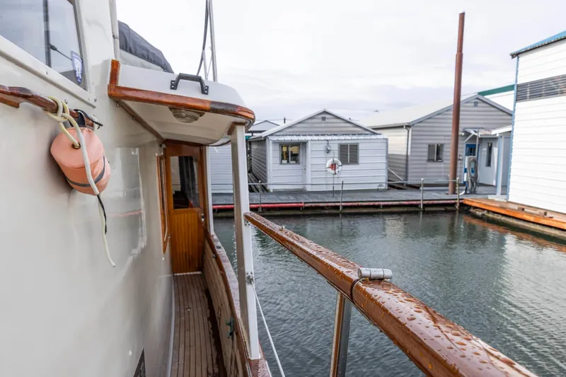 Slide: The Image of 1986 Kadey-Krogen 42 yacht docked near waterfront houses, showcasing wooden deck and railing. - 26