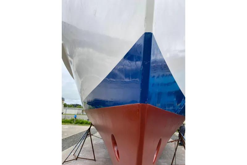 Slide: The Image of 1986 Kadey-Krogen 42 boat hull with blue and red paint, on stands. - 47