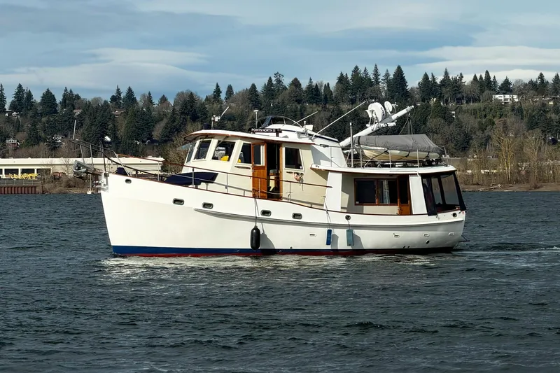Slide: The Image of 1986 Kadey-Krogen 42 yacht cruising on a scenic river with forested background. - 52