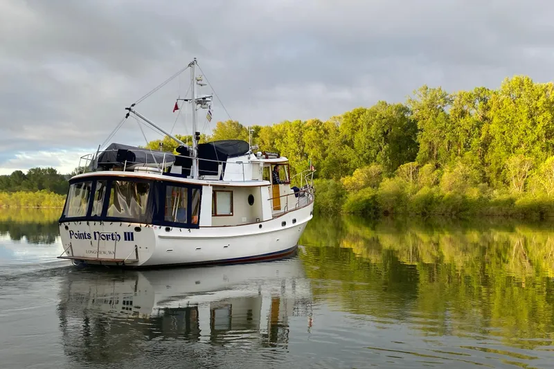 Slide: The Image of 1986 Kadey-Krogen 42 boat cruising on a serene river with lush green trees. - 53
