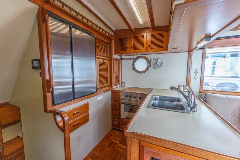 Slide: The Image of 1986 Kadey-Krogen 42 yacht kitchen with wooden cabinetry, dual sinks, and porthole window. - 6