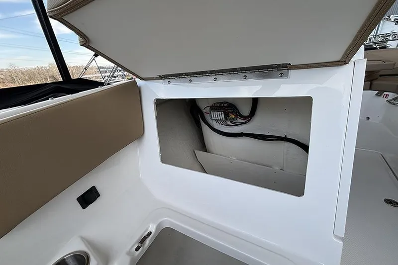 Slide: The Image of 2026 Bayliner V20i boat interior with beige seating, docked in a marina. - 19