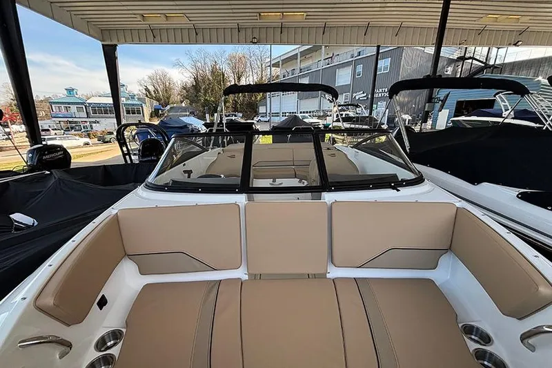 Slide: The Image of 2026 Bayliner V20i boat interior with beige seating, under a covered marina. - 27