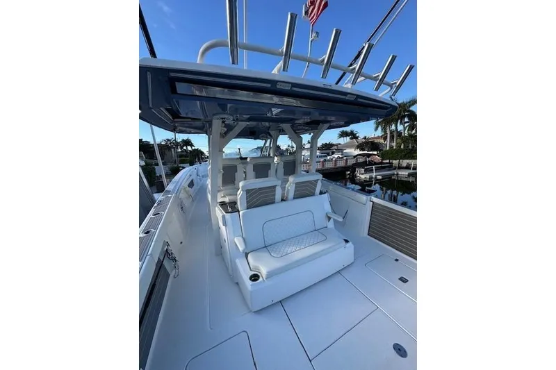Slide: The Image of 2023 Pursuit S 428 Sport boat interior with seating and rod holders, docked by palm trees. - 2