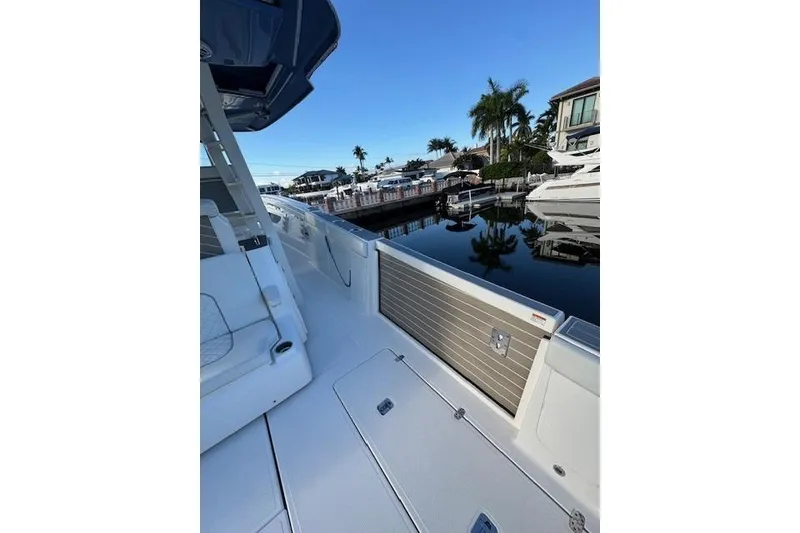 Slide: The Image of 2023 Pursuit S 428 Sport boat docked by waterfront homes and palm trees. - 6