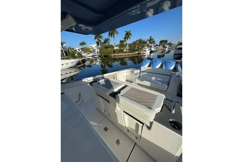 Slide: The Image of 2023 Pursuit S 428 Sport boat interior with seating, docked near palm trees. - 8