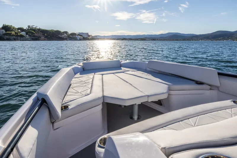 Slide: The Image of 2026 Axopar 29 CCX boat interior with cushioned seating on a sunny day. - 11