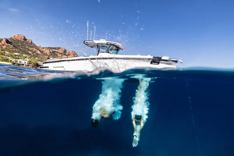 Slide: The Image of 2026 Axopar 29 CCX boat with divers in clear blue water. - 2