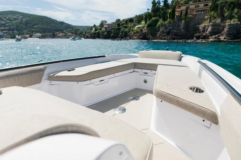 Slide: The Image of 2026 Axopar 29 CCX boat interior with cushioned seating, scenic coastal view. - 24