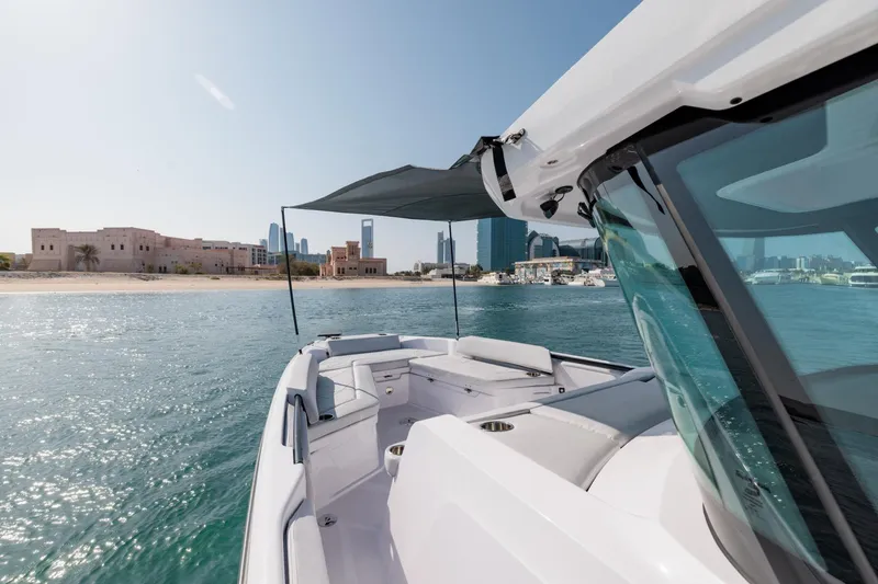 Slide: The Image of 2026 Axopar 29 CCX boat cruising near a scenic coastal city skyline. - 25