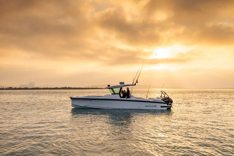 Slide: The Image of 2026 Axopar 29 CCX boat on calm water at sunset, with a golden sky backdrop. - 5