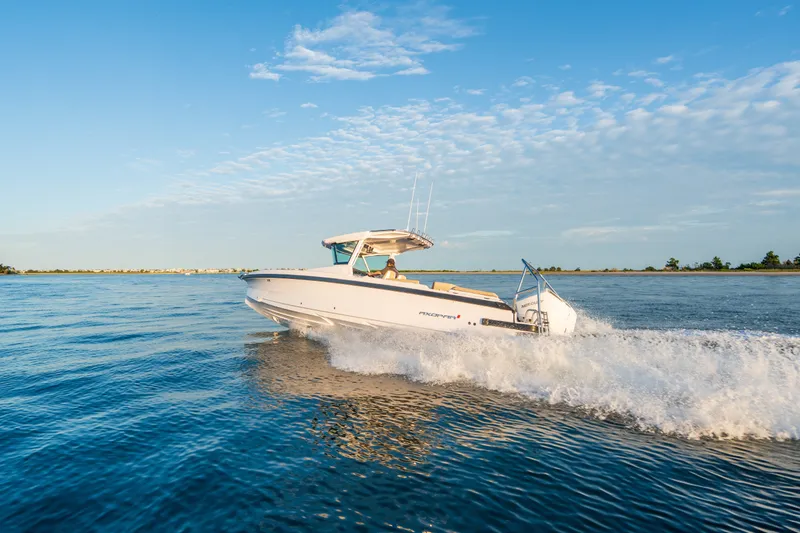 Slide: The Image of 2026 Axopar 29 CCX cruising on open water under a clear blue sky. - 23