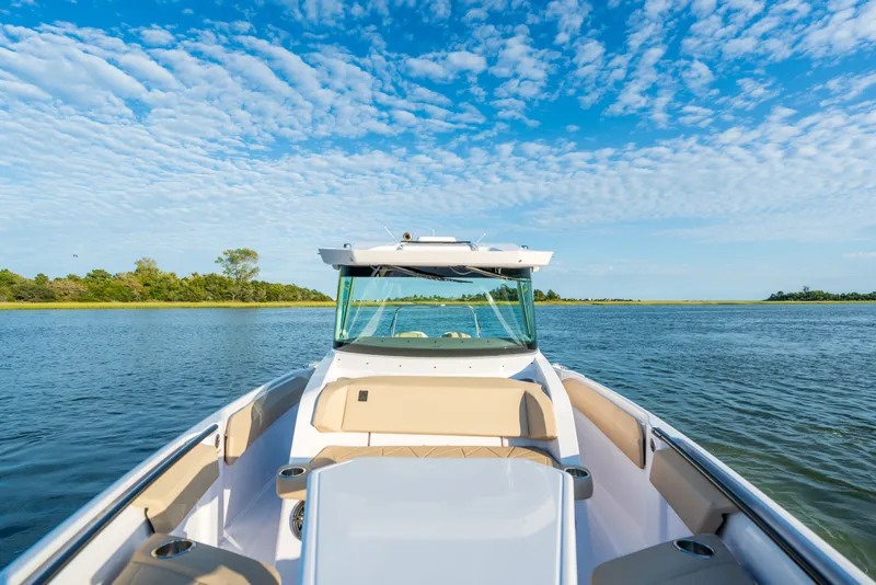Slide: The Image of 2026 Axopar 29 CCX boat cruising on a serene lake under a blue sky. - 27