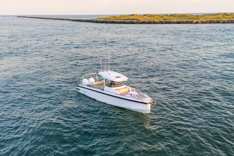 Slide: The Image of 2026 Axopar 29 CCX boat cruising on open water near a rocky shoreline. - 18