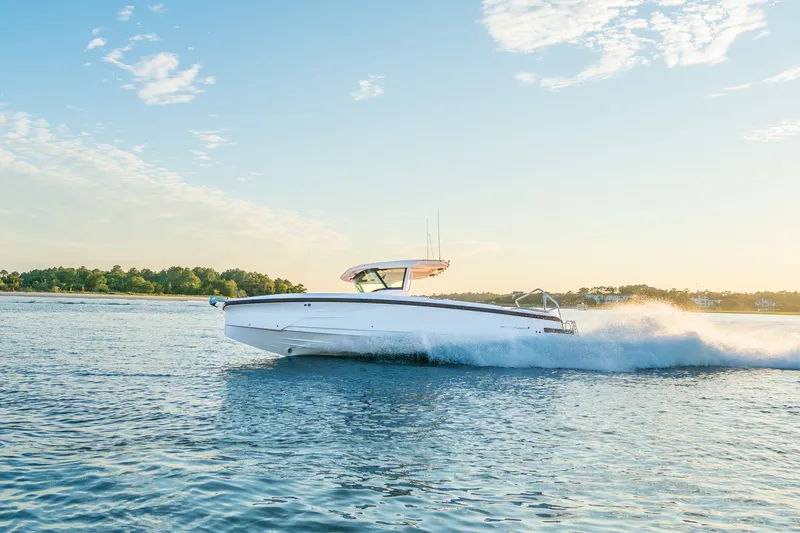 Slide: The Image of 2026 Axopar 29 CCX boat cruising on a sunny day, creating waves in open water. - 20