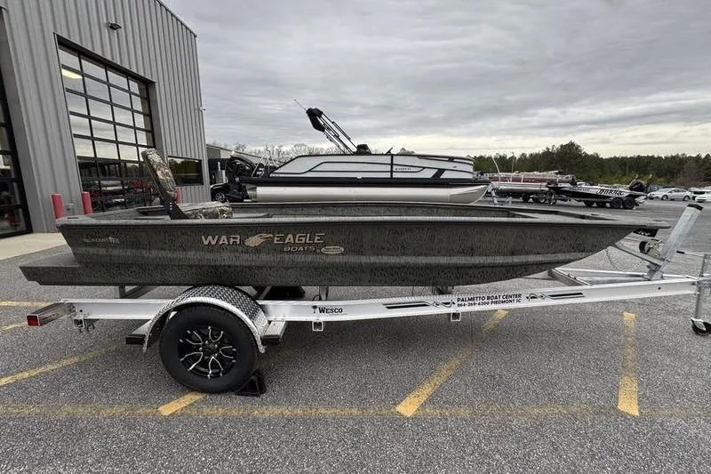 Slide: The Image of 2026 War Eagle 750 Gladiator boat on trailer, parked outside a building. - 2