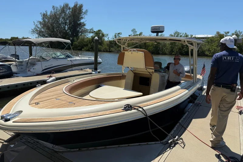 Slide: The Image of 2012 Chris-Craft Catalina 29 docked, featuring elegant design and spacious deck, with two people onboard. - 4