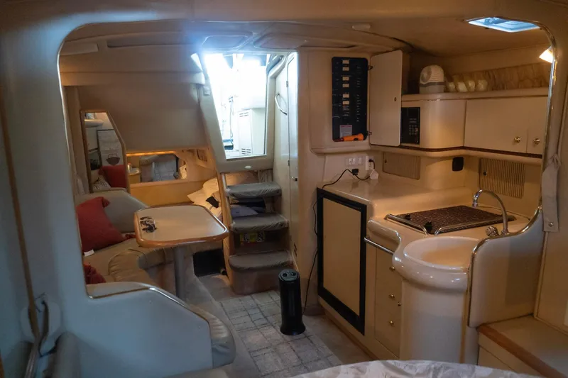 Slide: The Image of Interior of 1998 Sea Ray Sundancer 330 yacht, featuring cozy seating and compact kitchen area. - 18