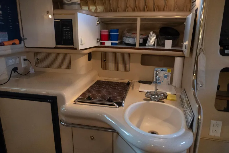 Slide: The Image of 1998 Sea Ray Sundancer 330 yacht kitchen with sink, stove, and storage cabinets. - 19
