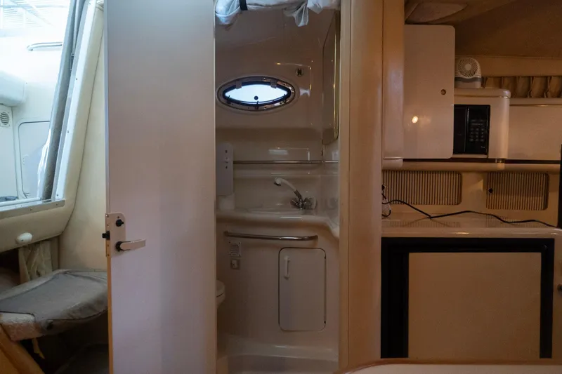 Slide: The Image of 1998 Sea Ray Sundancer 330 interior with kitchenette and bathroom, featuring compact design. - 23