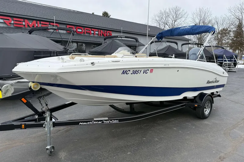 Slide: The Image of 2020 NauticStar 203 SC boat on trailer at dealership, featuring blue and white design. - 14