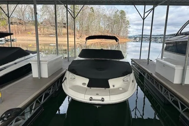 Slide: The Image of 2007 Chaparral Sunesta 254 boat docked under a covered marina on a calm lake. - 2